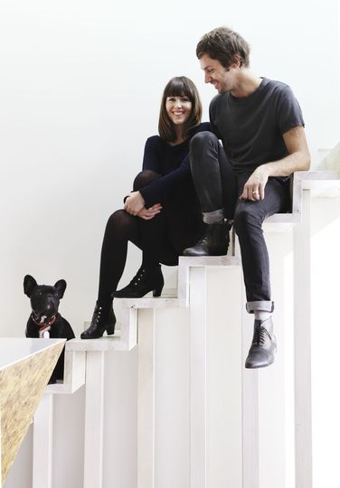 Ben Edwards, his partner and their pet dog sit on the stairs of their home Cubby House
