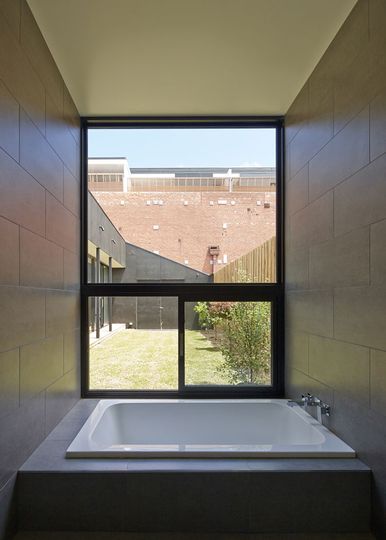 Engawa House bathroom overlooks lawn area and red brick warehouse