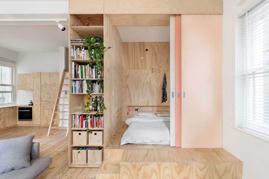 Flinders Lane Space Efficient Apartment bed is raised on a platform and separated from the living area by a Japanese-inspired screen