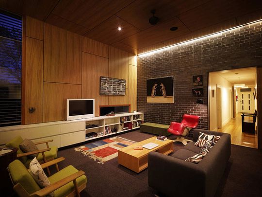 Haberfield House living area at night has dramatic lighting for glazed brick wall