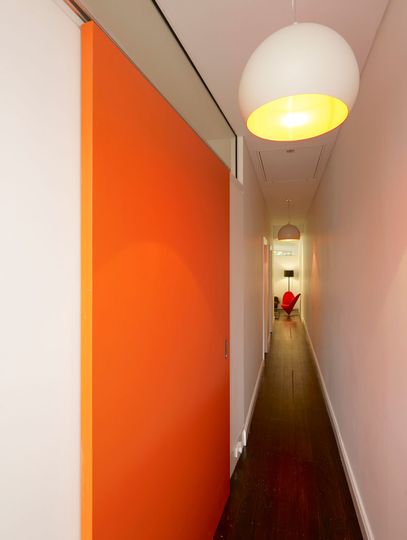 A long corridor runs past the bedroom in the existing part of the home, leading to the new living areas