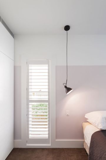 A simple reading lamp hangs from the ceiling in the bedroom -- a fun choice of lighting