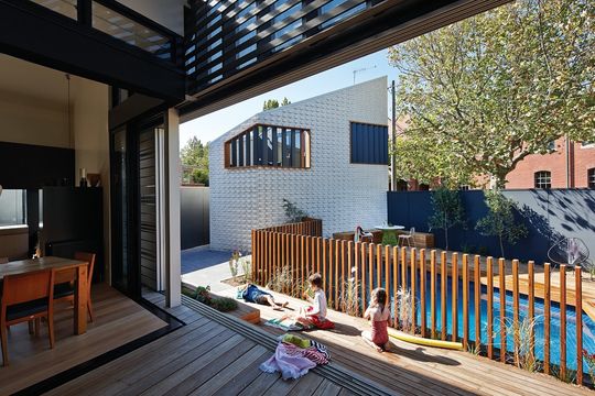 Children play around the pool on new decking area in the project House Reduction