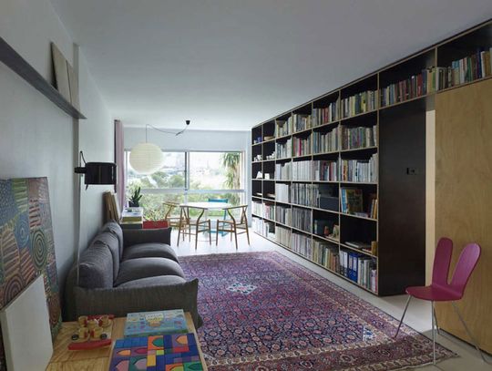 Potts Point Apartment living area is lined by bookshelves and storage to make the most of the small space