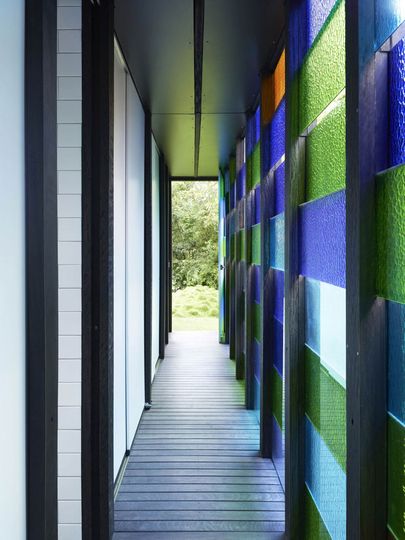 A hallway and storage area at Raven Street House is lit by varying colored panes of glass